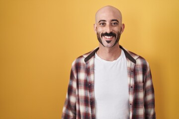 Hispanic man with beard standing over yellow background with a happy and cool smile on face. lucky person.