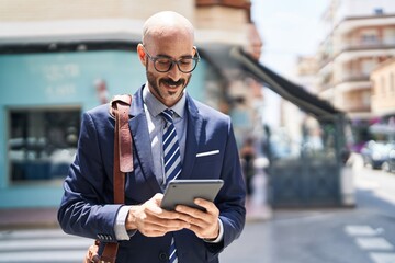 Young hispanic man executive smiling confident using touchpad at street