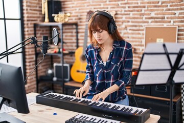 Young woman musician playing piano keyboard at music studio - obrazy, fototapety, plakaty