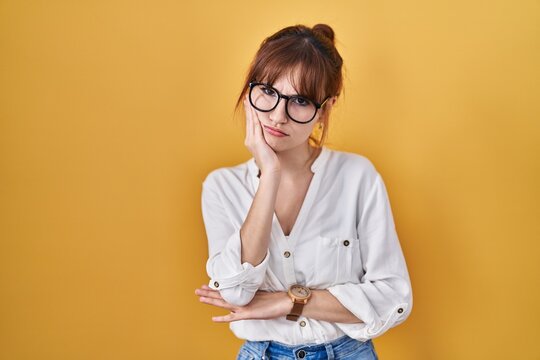 Young beautiful woman wearing casual shirt over yellow background thinking looking tired and bored with depression problems with crossed arms.