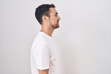 Handsome hispanic man standing over white background looking to side, relax profile pose with natural face and confident smile.