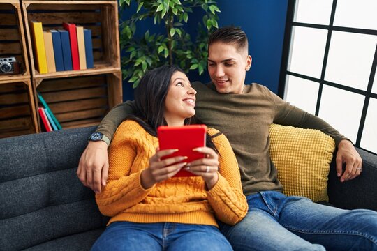 Man and woman couple hugging each other using touchpad at home
