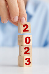 New year concept with wooden blocks, woman placing wooden block on top of others.