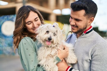 Man and woman holding dog standing together at street