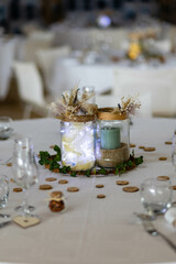 Table de mariage avec des verres, des décorations en bois, des lumières et des fleurs