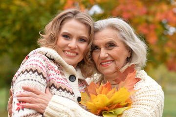 Portrait of an elderly woman with her daughter in autumn.