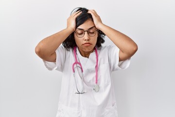 Young hispanic doctor woman wearing stethoscope over isolated background suffering from headache desperate and stressed because pain and migraine. hands on head.
