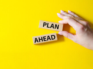 Plan ahead symbol. Wooden blocks with words 'Plan ahead'. Beautiful yellow background. Businessman hand. Business and 'Plan ahead' concept. Copy space.