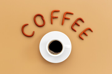 White cup of hot black coffee with rubber letters. Coffee break concept