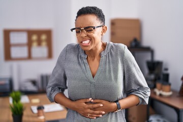 African american woman working at the office wearing glasses with hand on stomach because...