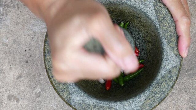 Hand pounding stone mortar with chili  and garlic pestle.
