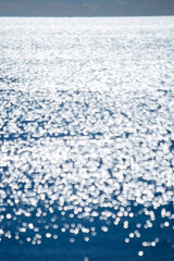 Abstract blurred background.Spots of white reflections of shining sun on blue surface of sea waves.Sea on sunny day.Natural blurry bokeh texture backdrop.Seamless looping.Beautiful natural background