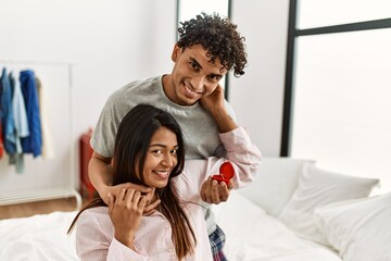 Obraz premium Young latin couple on marriage proposal holding engagement ring at the bedroom.