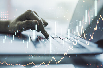 Double exposure of abstract creative financial chart with hand typing on computer keyboard on background, research and strategy concept