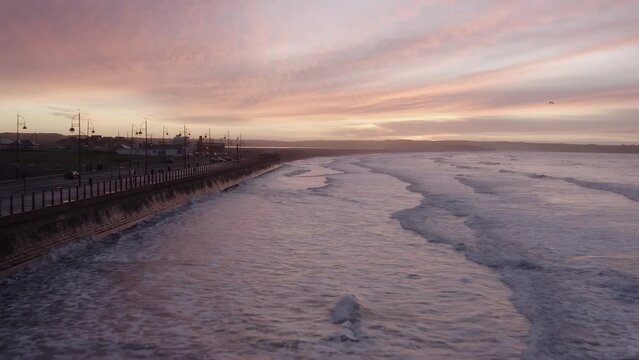 Waves reflect off seawall on Tramore Strand seaside at dawn sunrise