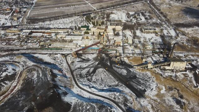 Aerial shot of factory for a fossil extraction at winter day. Drone flying over pit of industrial mining. Ecology and environmental pollution problem. Concept of production and manufacture