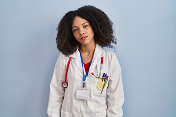 Young african american woman wearing doctor uniform and stethoscope looking sleepy and tired, exhausted for fatigue and hangover, lazy eyes in the morning.