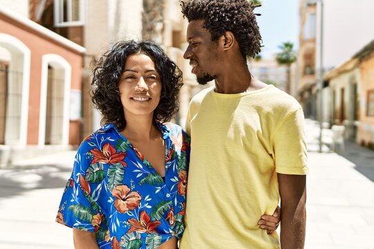 Young interracial couple smiling happy and hugging at the city.
