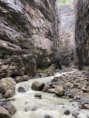 Rocky canyon in the Switzerland. Big rocks and boulders in the canyon. Summer day with blue sky canyon with green forest on the top. Huge canyon with river and waterfalls inside.
