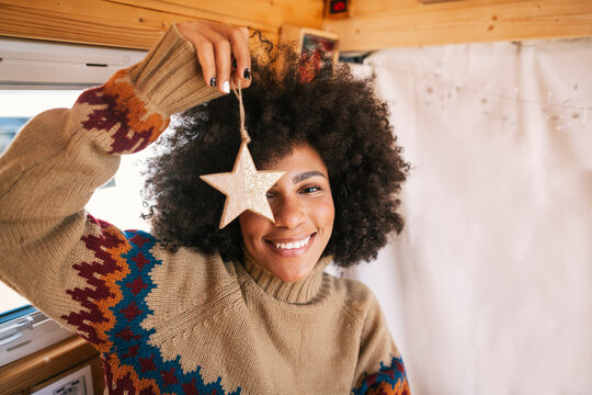 Afro girl smiles while showing a christmas star