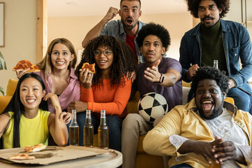 Multiracial friends watching match on television at home