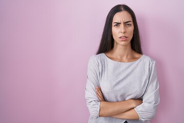 Fototapeta premium Young brunette woman standing over pink background skeptic and nervous, disapproving expression on face with crossed arms. negative person.