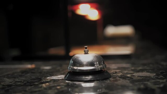 Silver Call Bell. close-up. hand presses service bell on the counter in the restaurant bar