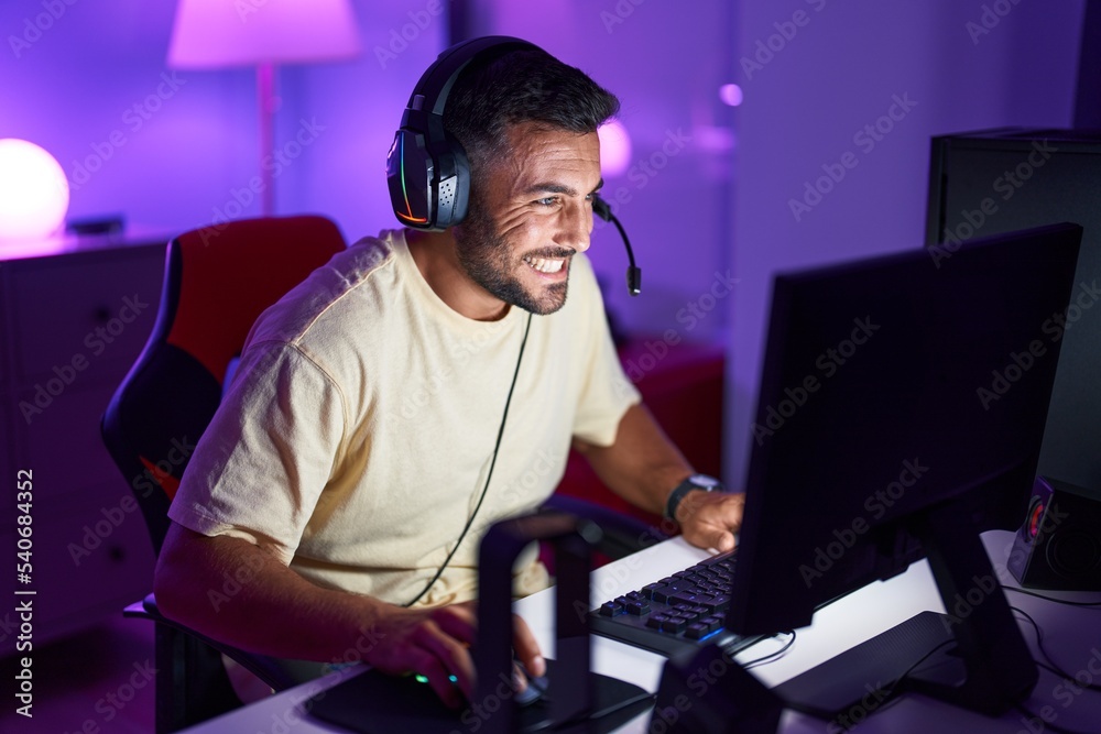 Canvas Prints Young hispanic man streamer playing video game using computer at gaming room