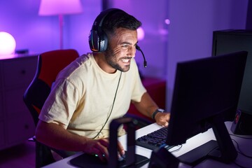 Young hispanic man streamer playing video game using computer at gaming room