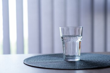 Glass of water on wooden table in room. Space for text