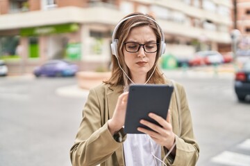 Young woman business worker using touchpad and headphones at street