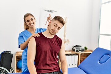 Young hispanic physioterapist woman make neck rehab treatment to man at the clinic.