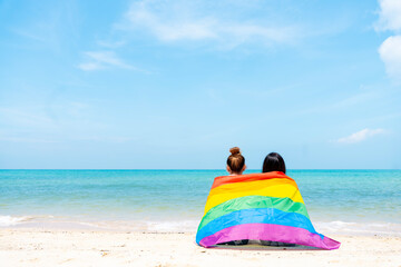 lesbian couple with LGBTQ flags on the beach, happy couple on vacation together at sea