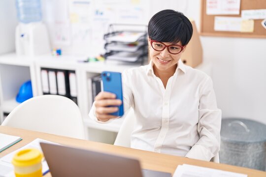 Middle age chinese woman business worker make selfie by smartphone at office