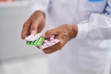 Senior grey-haired man pharmacist holding pills tablets at pharmacy