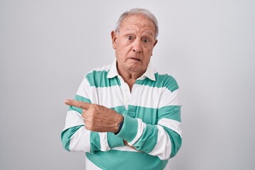 Senior man with grey hair standing over white background pointing aside worried and nervous with forefinger, concerned and surprised expression