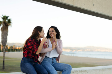 A beautiful lesbian young couple embraces. Girls drinking juice. LGBT community