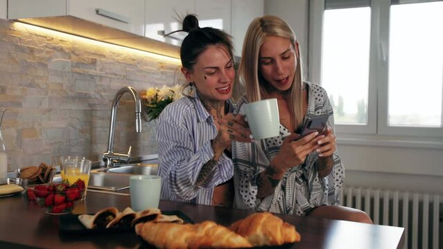 Lesbian couple having coffee browsing phone