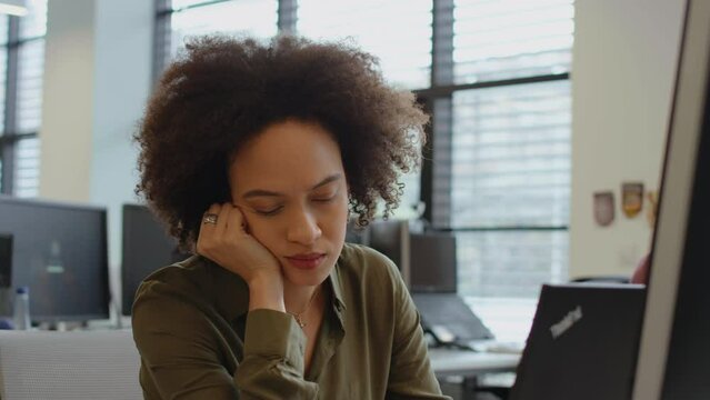 Young exhausted office worker feeling sleepy at work station