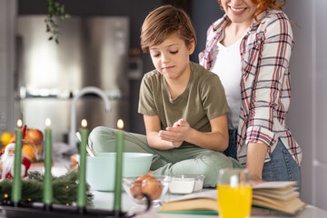 Shot of young women playing with her son, smiling while he is sitting on kitchen table.
Having fun while making cookies, leisure time
Family time stock photo