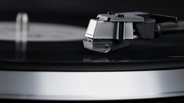 Close-up turntable record player with vinyl disc. Macro video. Video turntable player with black vinyl record, stylus and turntable.