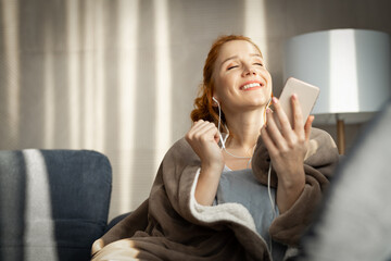 Adult woman enjoying her free time at home listening music and using mobile phone