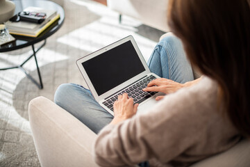 Naklejka premium Unrecognizable woman relaxing in the armchair and using a laptop