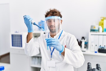 Young hispanic man wearing scientist uniform working at laboratory