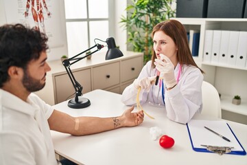 Man and woman wearing doctor uniform holding blood sample test tube at clinic