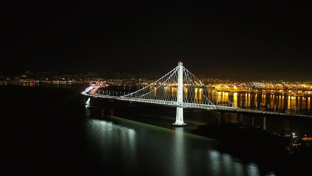 Aerial Shot Of Cars Moving On Famous Suspension Bridge, Drone Flying Backwards Over Strait At Night - San Francisco, California