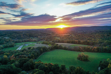Brilliant Sunset in early fall over Wantage Township Sussex County NJ with large fields and foliage and Kittatiny Mountains in background aerial
