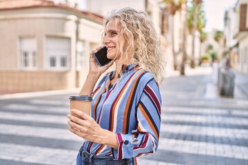 Fototapeta premium Middle age blonde woman talking on the smartphone drinking coffee at street