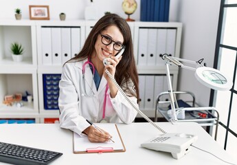 Obraz na płótnie Canvas Young hispanic woman wearing doctor uniform working at clinic