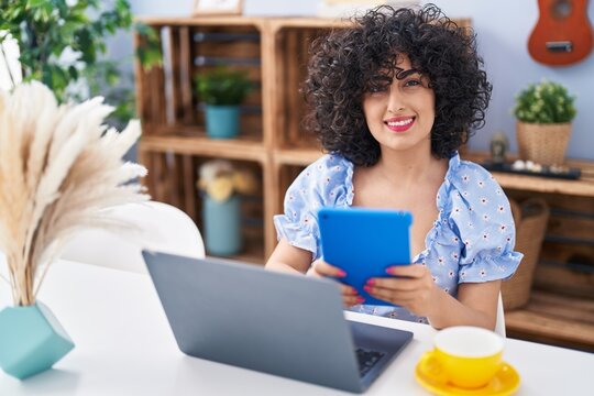 Young middle east woman using laptop and touchpad sitting on table at home